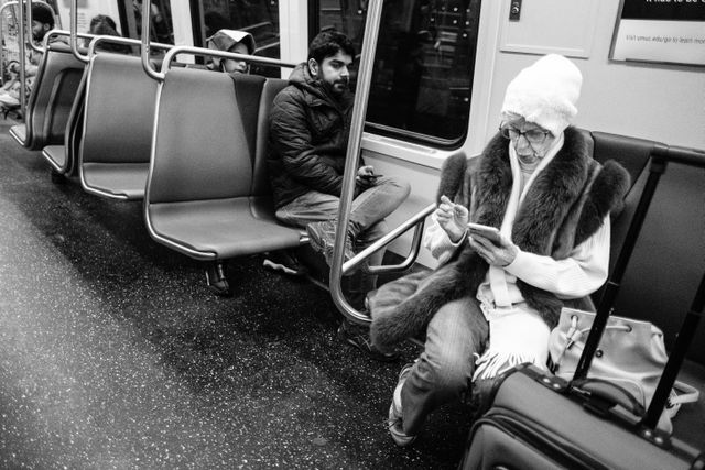 A passenger looking at her phone aboard a Metro train.