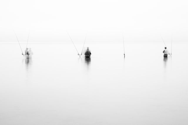 Three fishermen standing waist-deep in Lake Michigan, in deep fog.