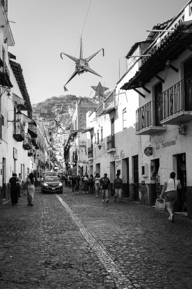 People and cars on a street in Taxco.