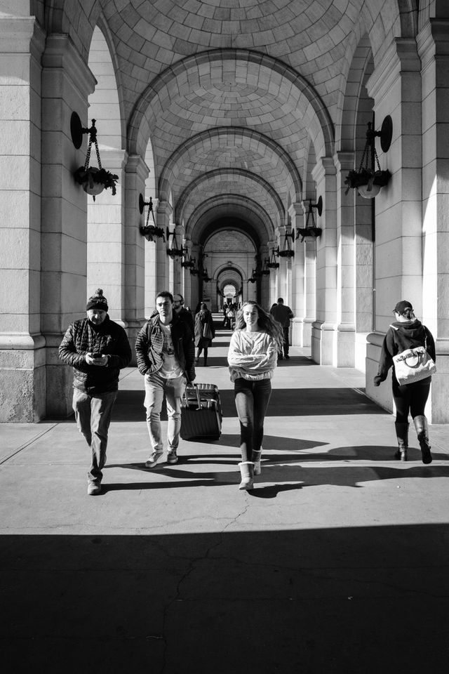 Pedestrians walking along the arches of Union Station.