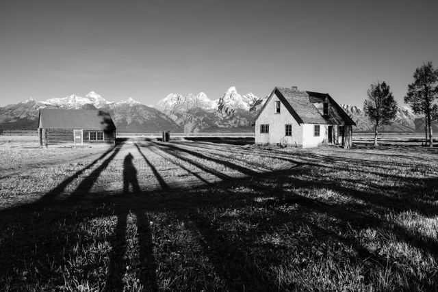 The pink stucco house and one of the log cabins at Mormon Row in Grand Teton National Park, with the Tetons in the background. My shadow is between the two structures.