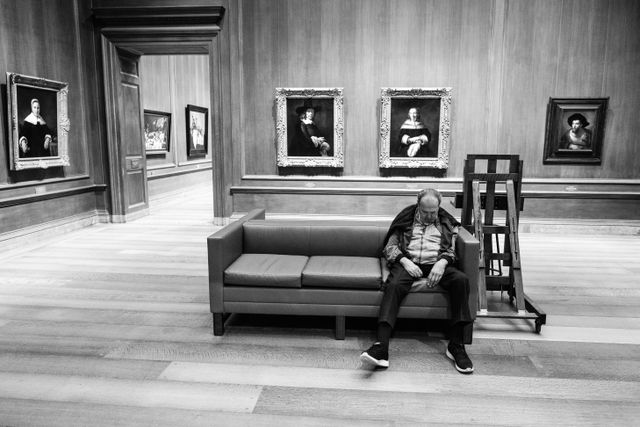 A man asleep on a couch at the National Gallery of Art.