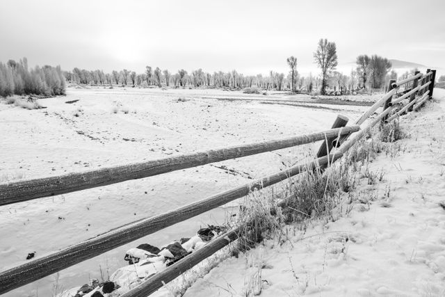 A wooden fence covered in frost in front of the Gros Ventre River, near Jackson, Wyoming.