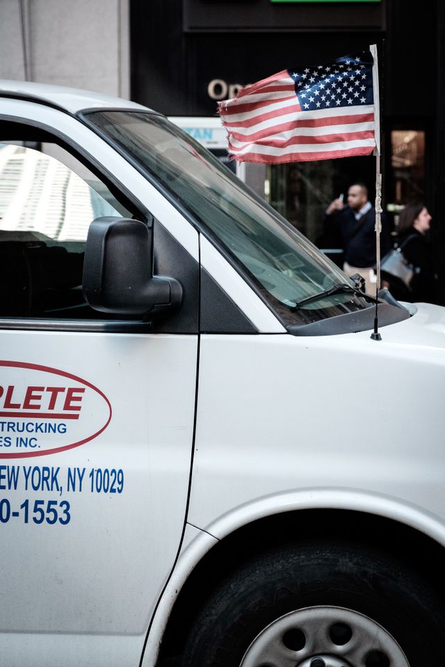 A white van with an American flag flying from its antenna.