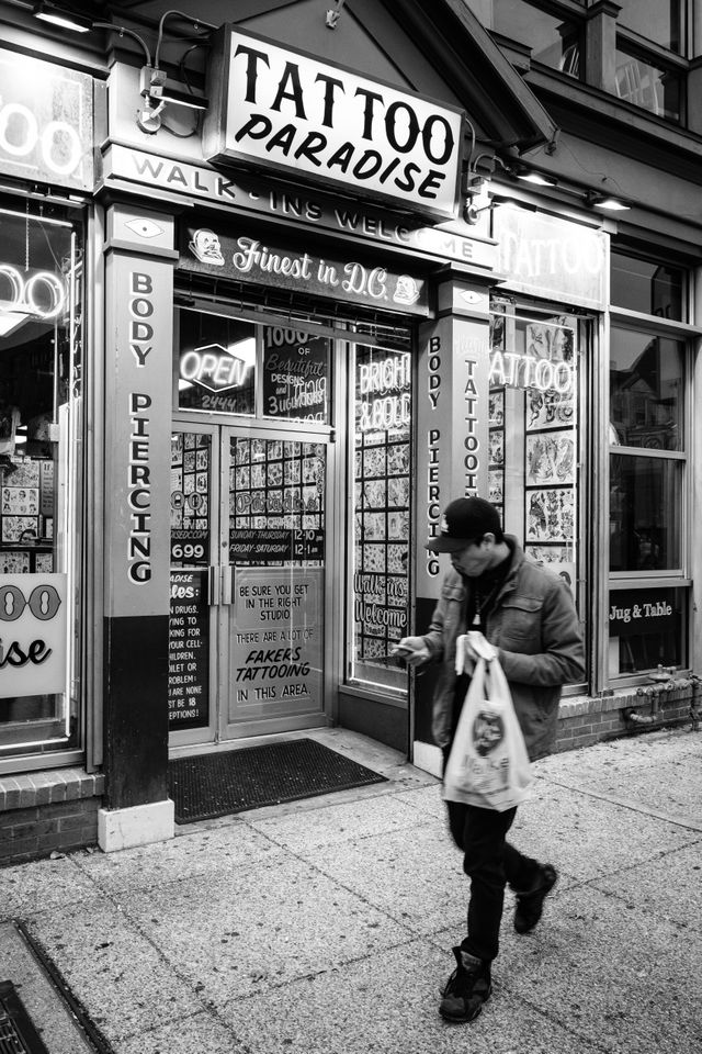 A man walking in front of the Tattoo Paradise in Adams Morgan.