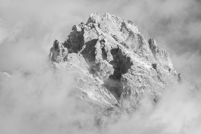 The summit of Teewinot Mountain seen among clouds.