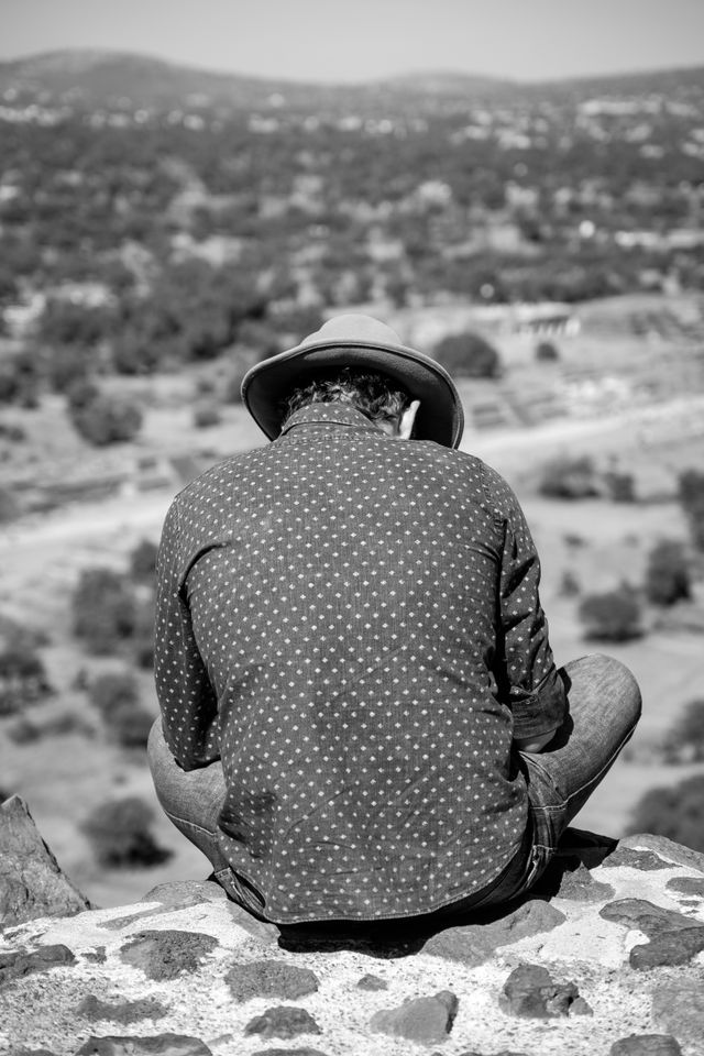 A tourist sitting at the edge of the Pyramid of the Sun in Teotihuacán.