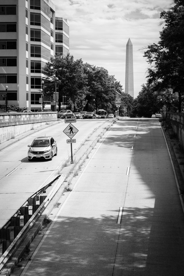 A car driving on an avenue in DC, with the Washington Monument in the background.