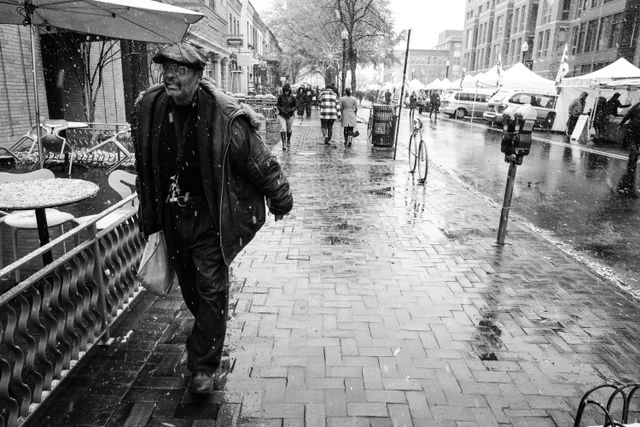 A man walking on the sidewalk near Eastern Market on a snowy day.