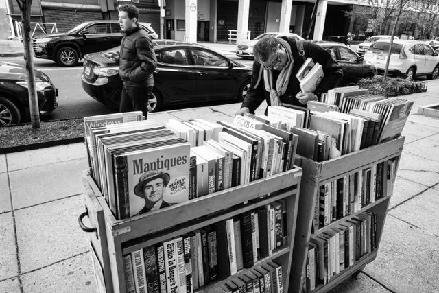 A woman looking at books for sale on the sidewalk outside Second Story Books in Dupont Circle.