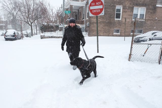 A man and his owner going for a walk during a blizzard.