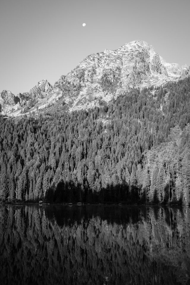 The Moon setting behind Mount Saint John, with String Lake in the foreground.