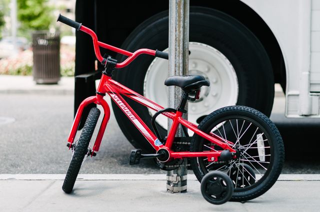 A tiny red bike chained to a street sign.