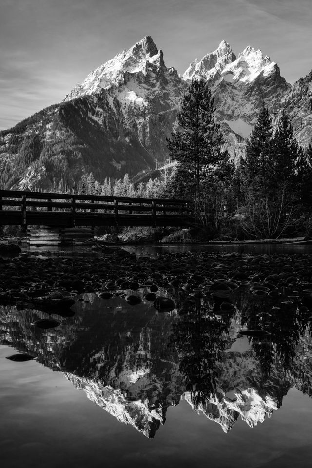 The Cathedral Group of the Tetons, Teewinot Mountain, Grand Teton, and Mount Owen, seen reflected in the outlet of String Lake.