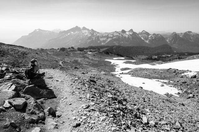 Kate, sitting on a rock by the Skyline Trail, admiring the scenery of Mount Rainier National Park.