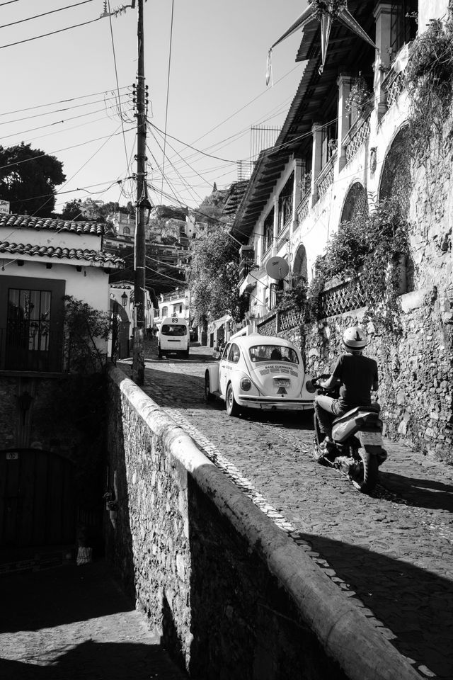 Traffic driving uphill on a street in Taxco.