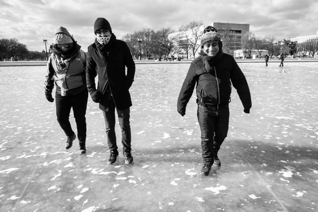 A group of people very carefully walking on the frozen Capitol Reflecting Pool.