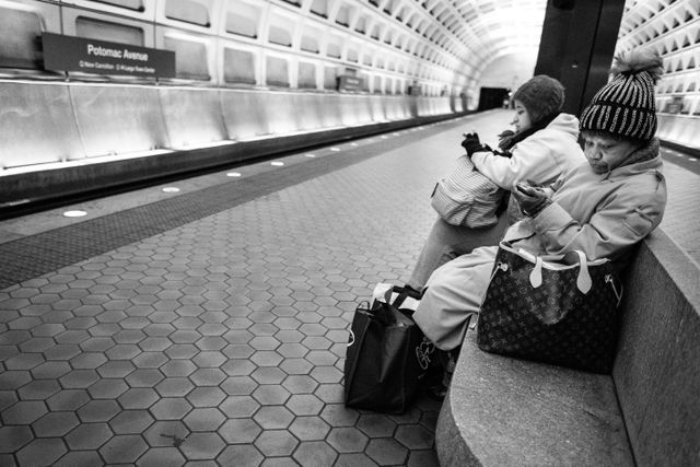 Two women sitting on a bench at the Potomac Avenue Metro Station.