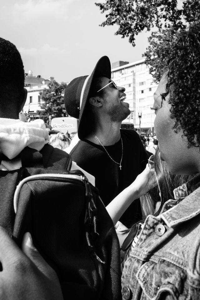 A person in a hat, laughing in the crowd of the Capital Pride Parade in Washington, DC.