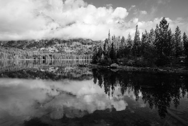 Reflections on Taggart Lake. In the background, Nez Perce Peak and Teewinot Mountain shrouded in clouds.