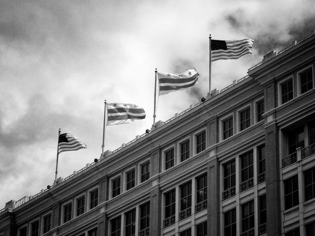 DC & American flags at the top of a building in DC.