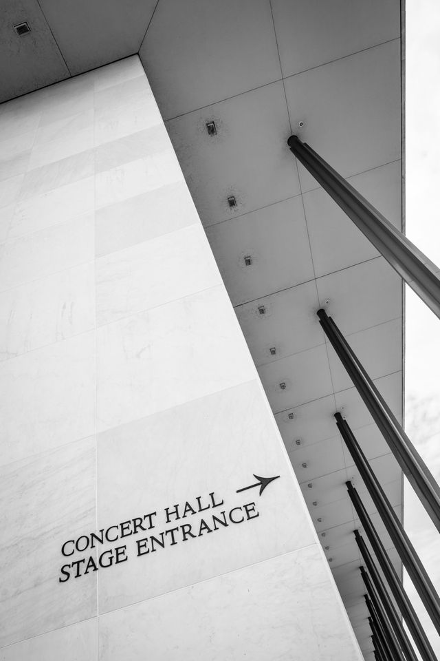 The columns and roof of the Kennedy Center, with a sign pointing to the Concert Hall and Stage Entrance.