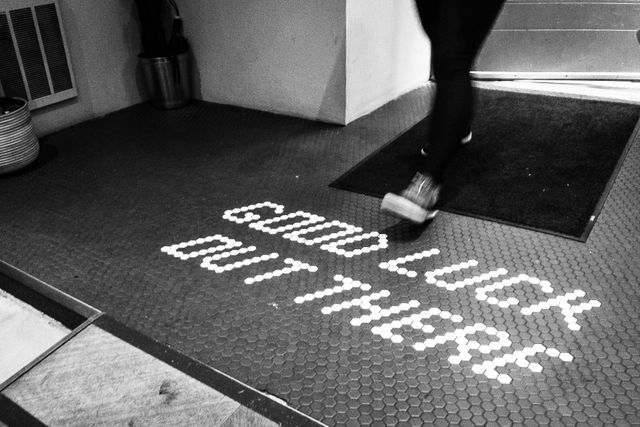 A person walking into Black Fox Coffee, where "good luck out there" is written in the tiles on the floor.