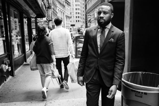 A man in a suit walking on a sidewalk in Manhattan's Financial District.