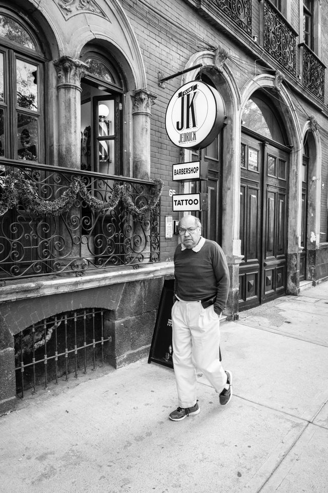 A man walking past a barbershop on Avenida Álvaro Obregón in Mexico City.