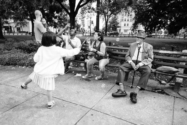 People blowing soap bubbles sitting on the benches of Dupont Circle.