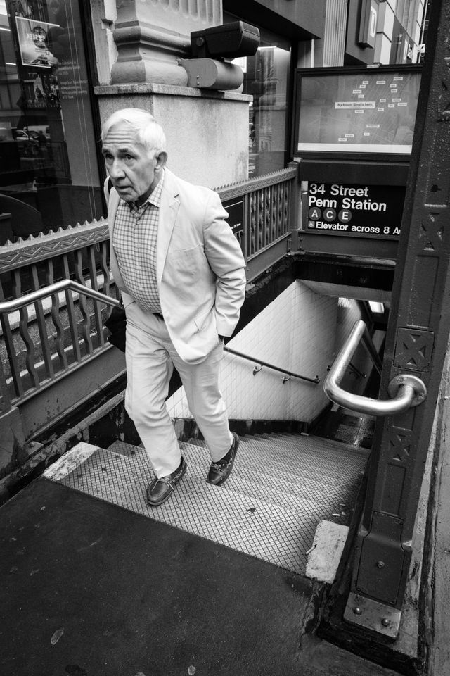 A person in a white suit exiting the 34th Street Penn Station subway station in New York City.