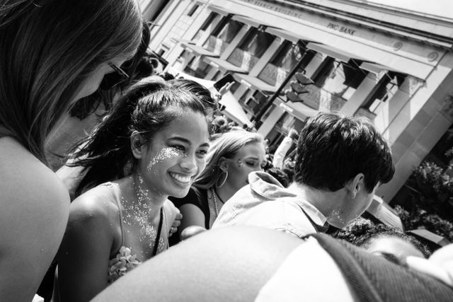 A person in the crowd of the Capital Pride Parade, smiling and covered in glitter.