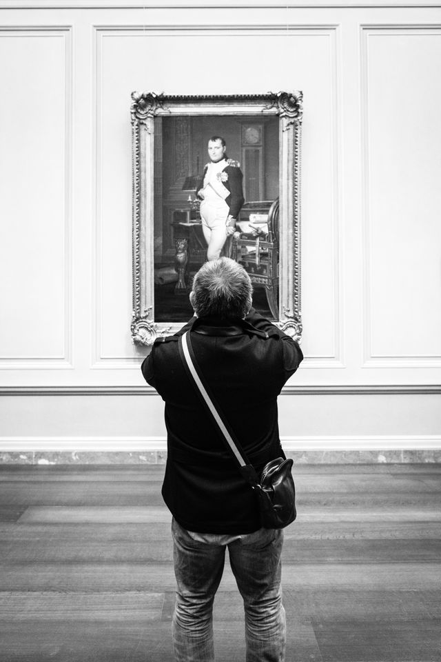 A man taking a photo of a portrait of Napoleon at the National Gallery of Art.