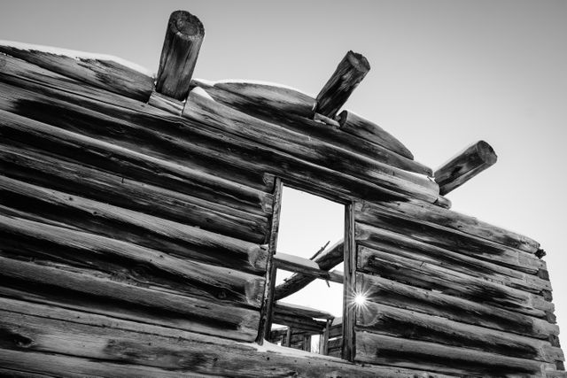 The facade and window of the Shane Cabin at Grand Teton National Park, with the sun shining between the logs.