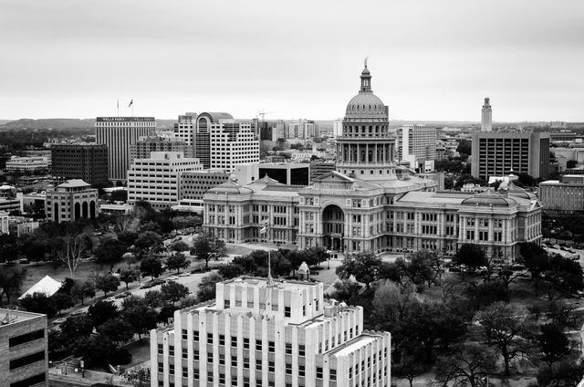 Black and white view of the Texas State Capitol from a nearby rooftop.