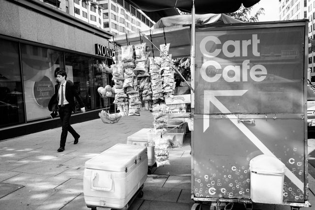 A man walking past a food cart on 18th street NW in DC.