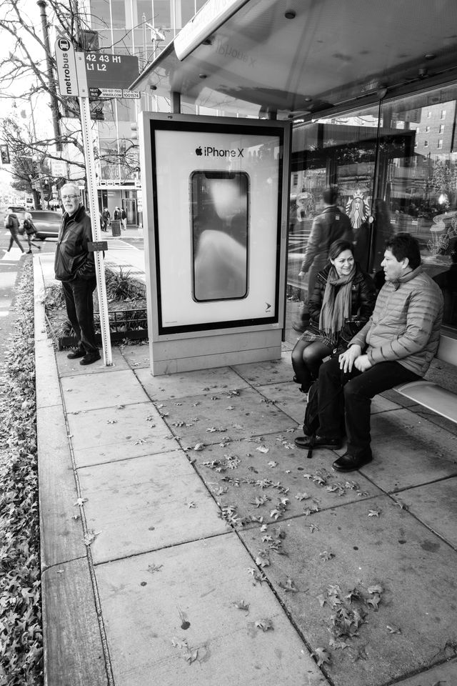 People sitting at a bus stop on Connecticut Avenue NW.