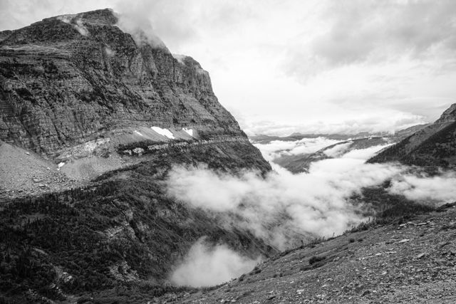 Mount Oberlin next to a cloud-filled valley on a cloudy day, as seen from the Going-to-the-Sun Road.