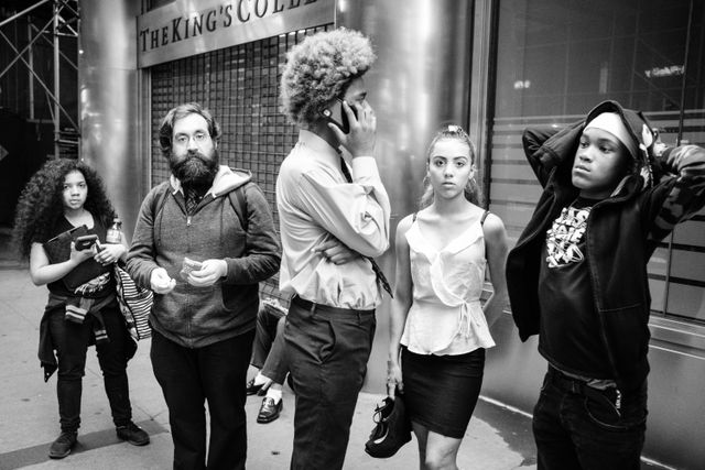 Five people waiting in line for something, on Broadway, in the Financial District.