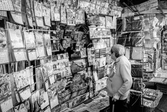 An old woman shopping at a newsstand in the historic center of Mexico City.