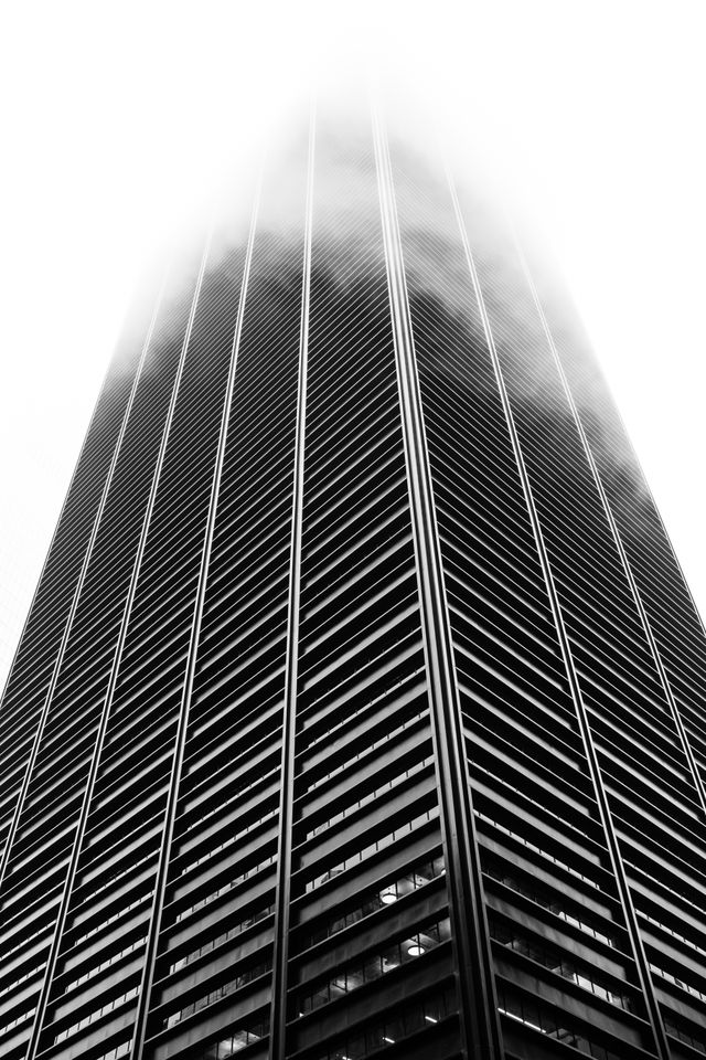 A building in New York's Financial District, with its top completely shrouded in fog.