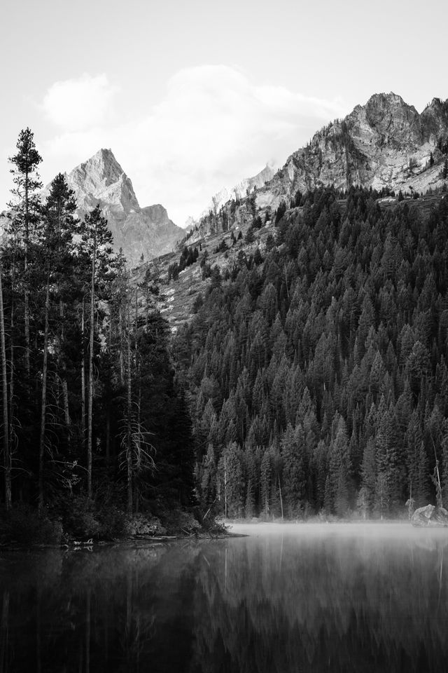 Mist floating over the surface of String Lake at dawn. In the background, Teewinot Mountain and Symmetry Spire.