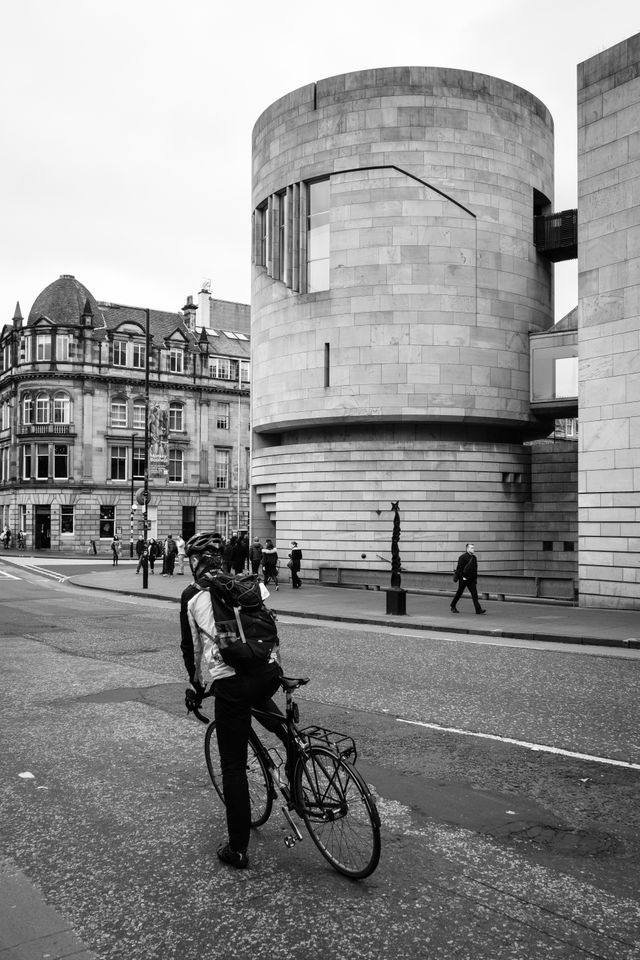 A cyclist stopped in front of the National Museum of Scotland.