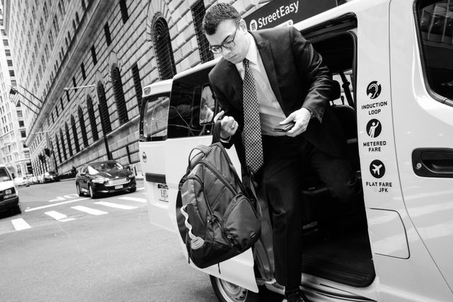 A man in a suit exiting a cab on William Street in New York City.