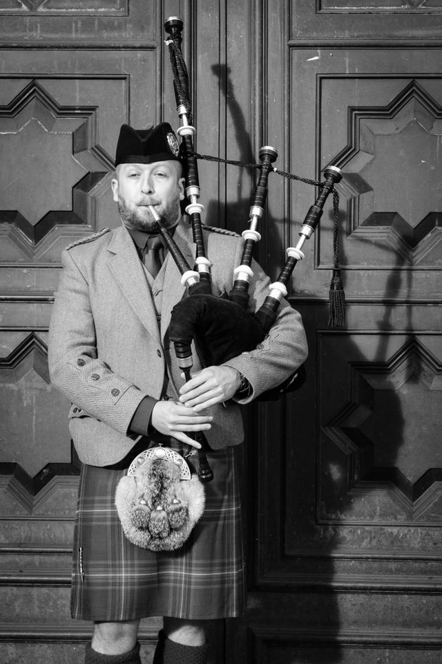 A man playing the bagpipes on the Royal Mile of Edinburgh.