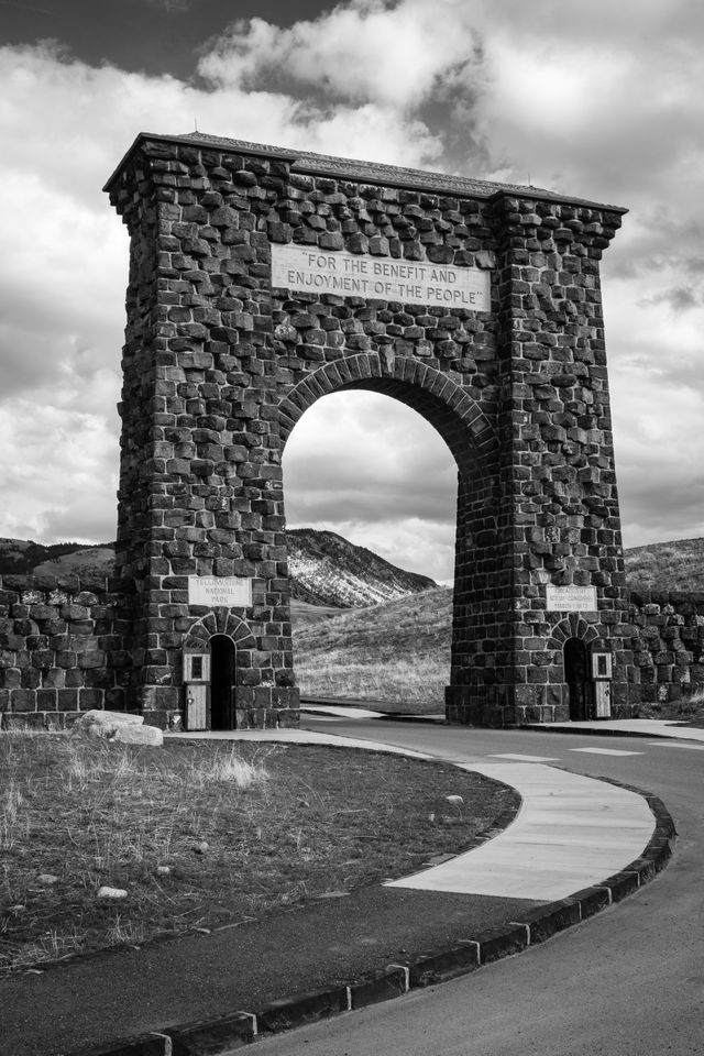 The Roosevelt Arch at Yellowstone National Park on a sunny afternoon. The inscription at the top reads "for the benefit and enjoyment of the people".