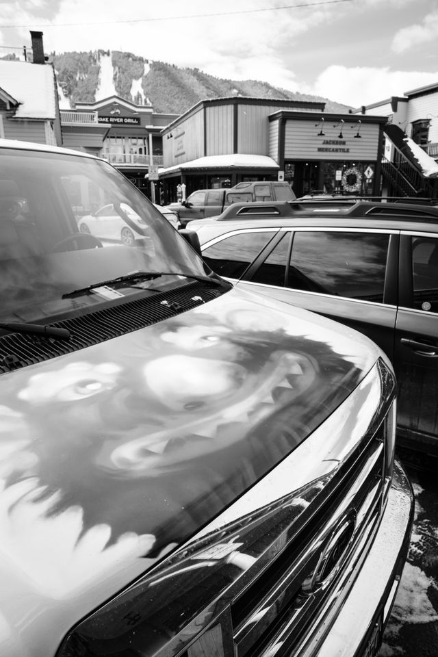 A white van parked in Jackson, Wyoming, with a grotesque clown monster thing painted on the hood.