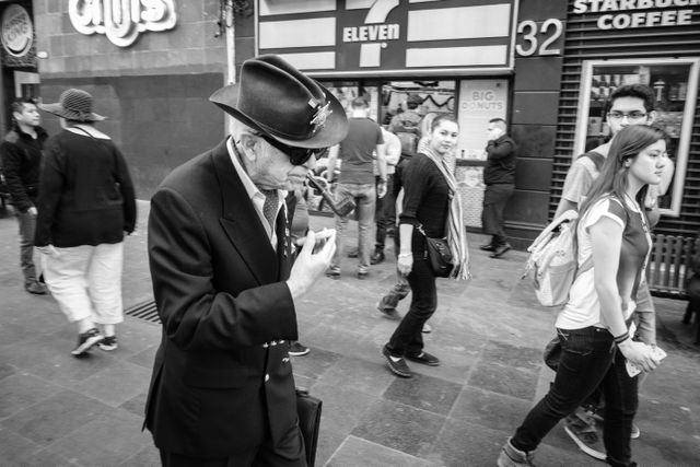 A man in a hat smoking a pipe while walking down the street.