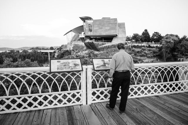 A man looking at information signs on the Walnut Street Bridge in Chattanooga, in front of the Hunter Museum.