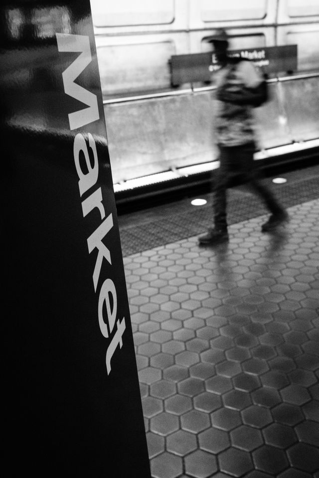 A man walking past a sign with "Eastern Market" written on it on the platform at Eastern Market Metro Station in Washington, DC.